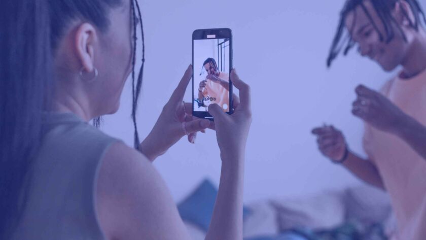 Woman filming a man who is dancing with her mobile phone.