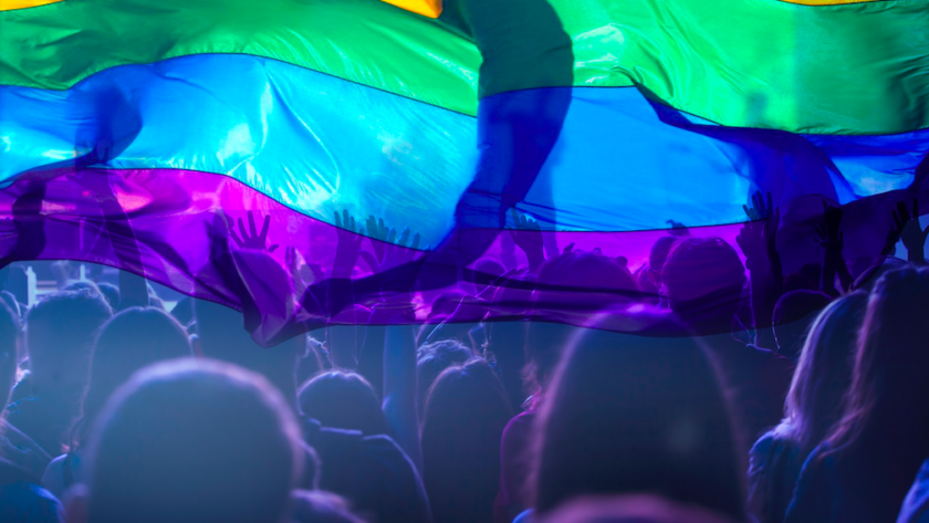 People celebrating and holding up a rainbow flag