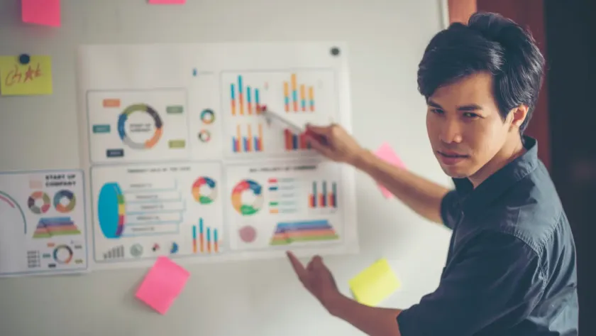 Person presenting SEO and marketing performance charts on a whiteboard, highlighting data trends and benchmarks